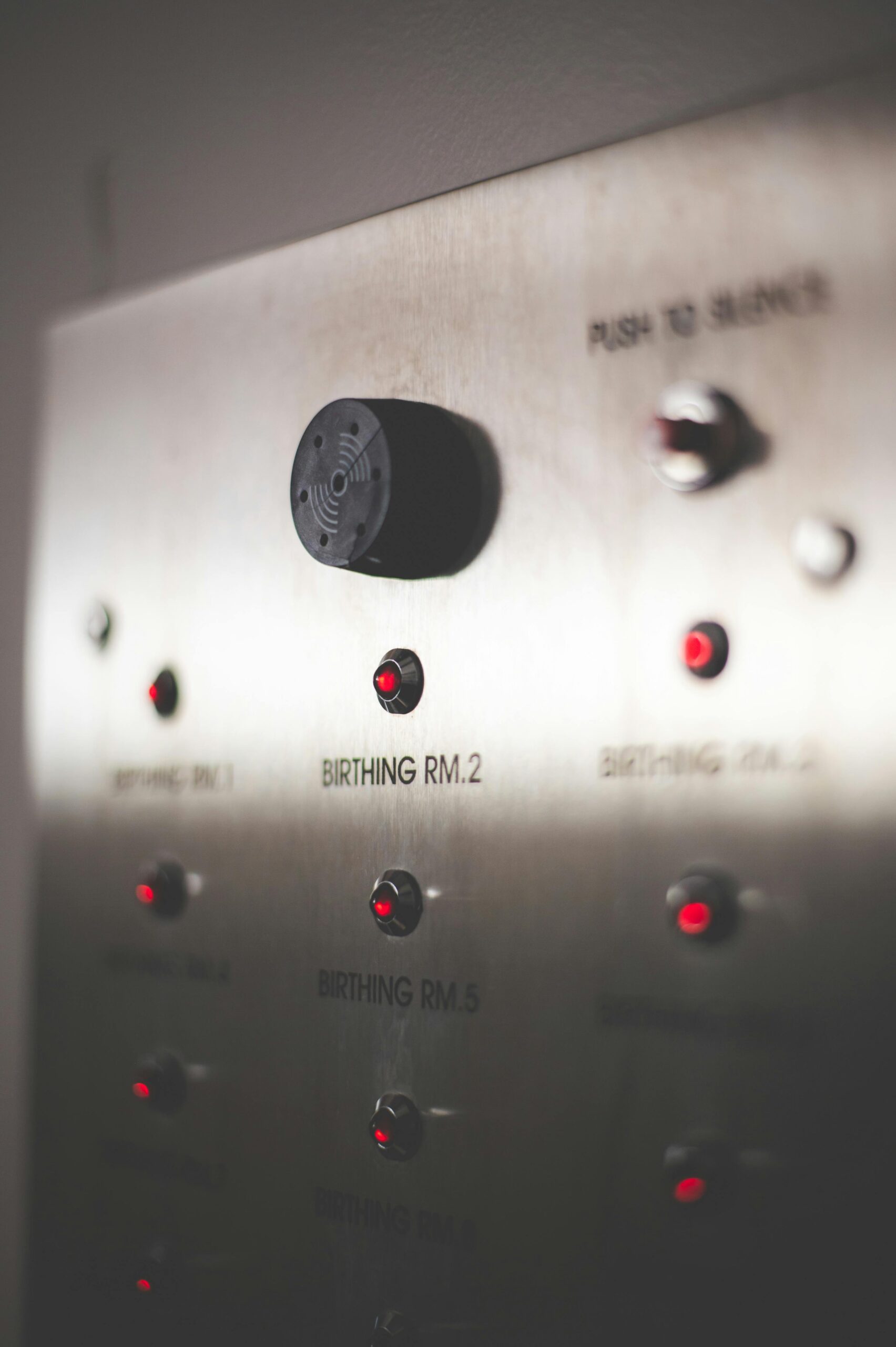 Close-up of an elevator control panel highlighting the maternity wing in a dimly lit hospital setting.